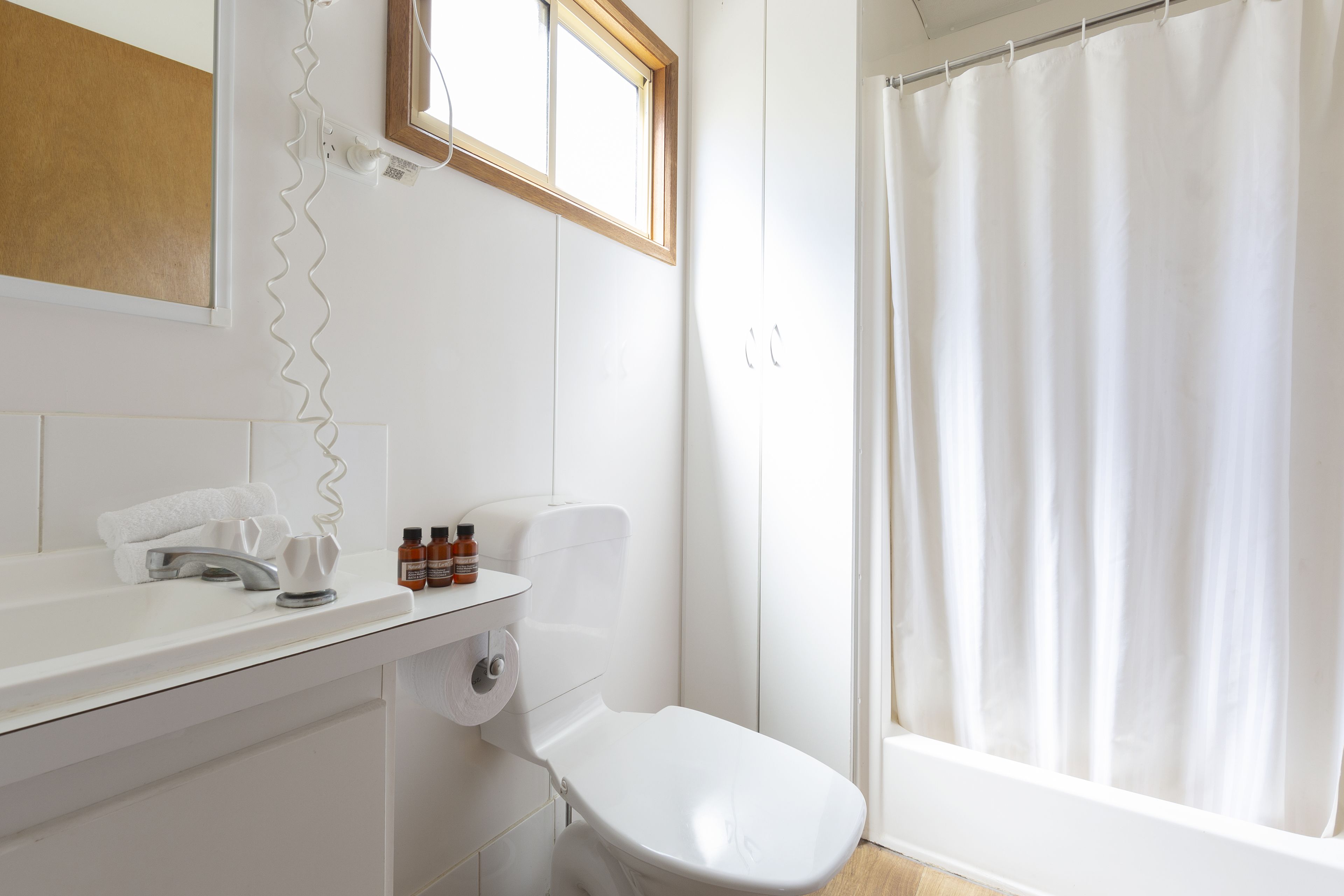 Un baño con inodoro, lavamanos y cortina de ducha.