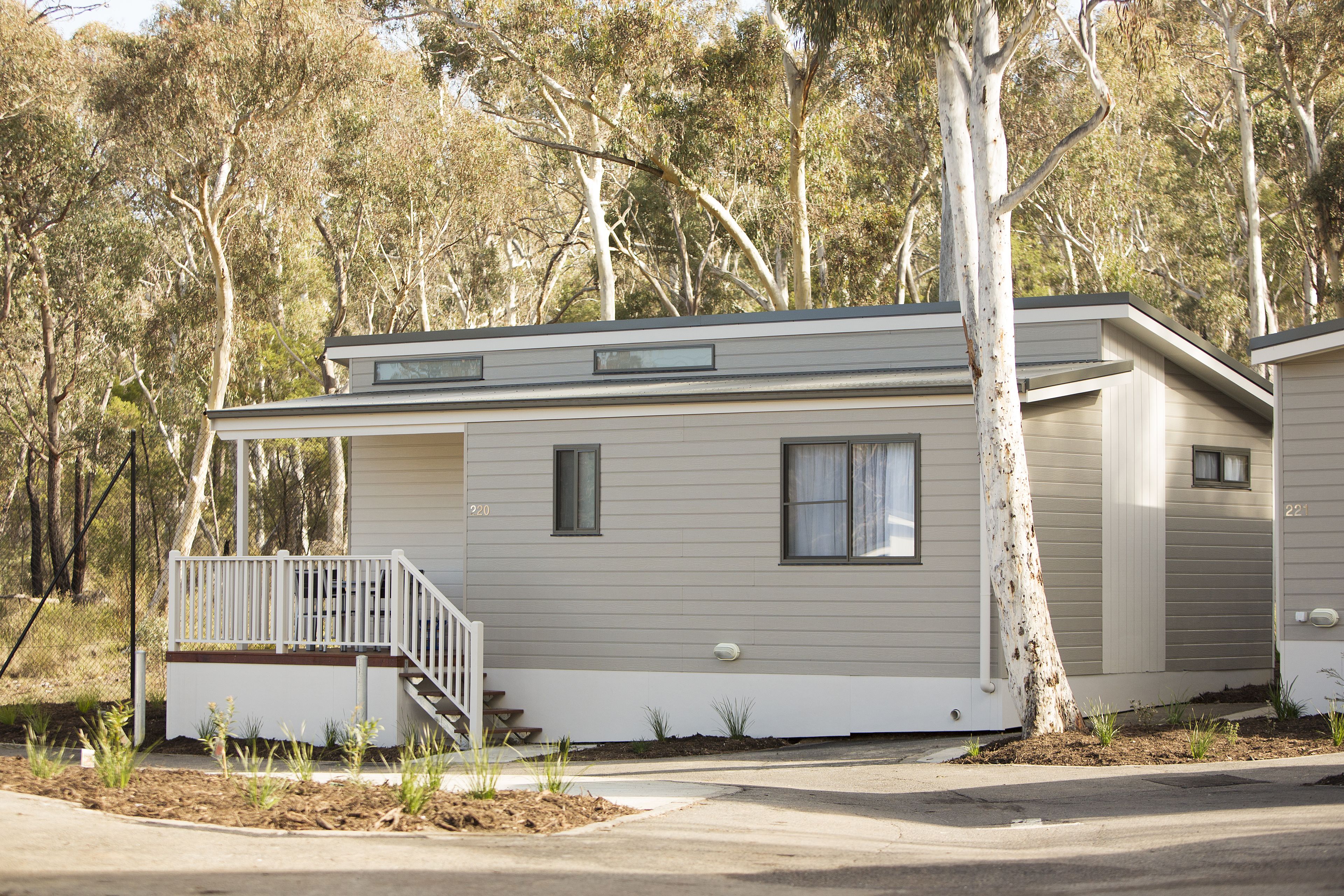 A single-story mobile home with a front porch, a small window, and a door.