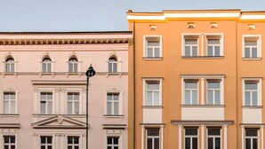 Ein mehrstöckiges Gebäude im klassischen Stil, mit symmetrischen Fenstern und einem zentralen Eingang mit Giebel.