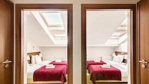 Ein Hotelzimmer mit zwei Betten, roten Bettdecken, einem Oberlicht und einem grünen Teppich – spiegelbildlich abgebildet.
