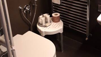 A modern bathroom with a toilet, a towel rack, and a small sink with toiletries.