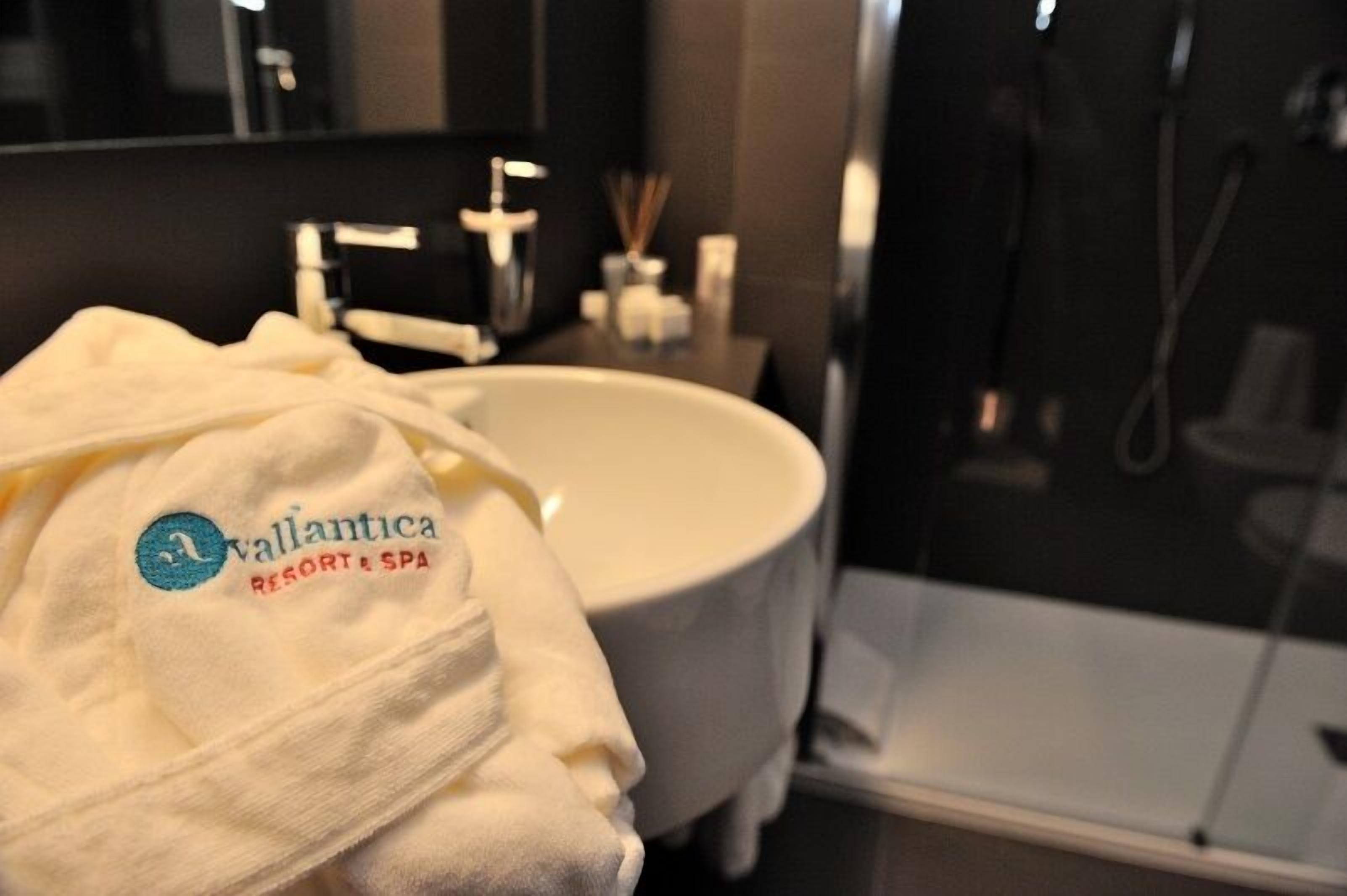 A bathroom with a white sink, a mirror, and a towel with 'Vallantica Resort & Spa' logo.