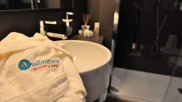 Et badeværelse med en hvid vask, et spejl og et håndklæde med logoet 'Vallantica Resort & Spa'.
