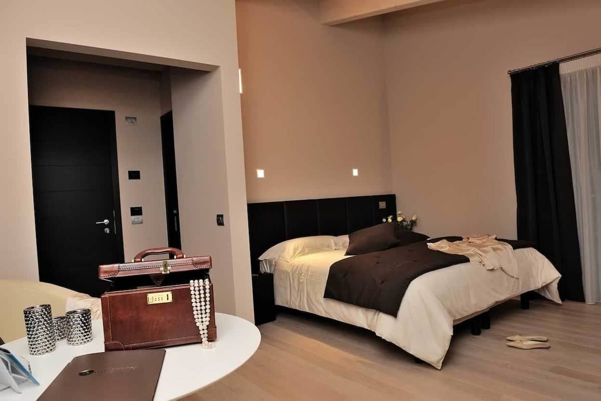 Ein Hotelzimmer mit Bett, Nachttisch und Koffer.