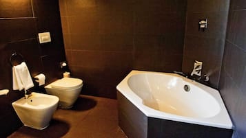 Un baño moderno con una bañera independiente, un bidé y un inodoro.
