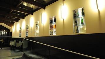 A modern interior with a staircase, glass railings, and shelves displaying bottles.