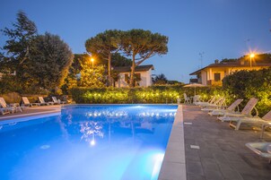 Una piscina al aire libre, sombrillas, tumbonas