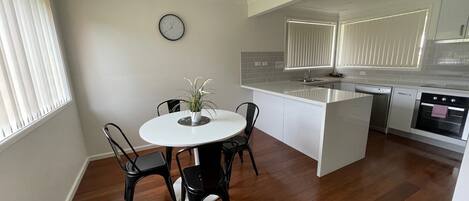 A modern kitchen with a central island, white cabinetry, and a built-in oven.