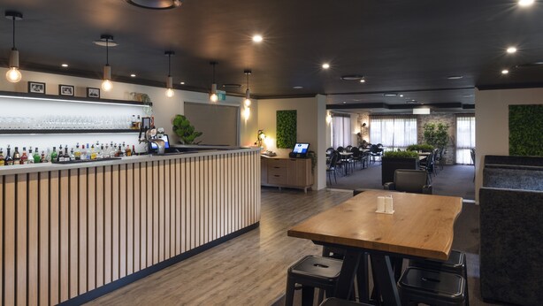 A modern restaurant with a bar area, wooden tables, and chairs. - Zig Zag Motel (Lithgow)