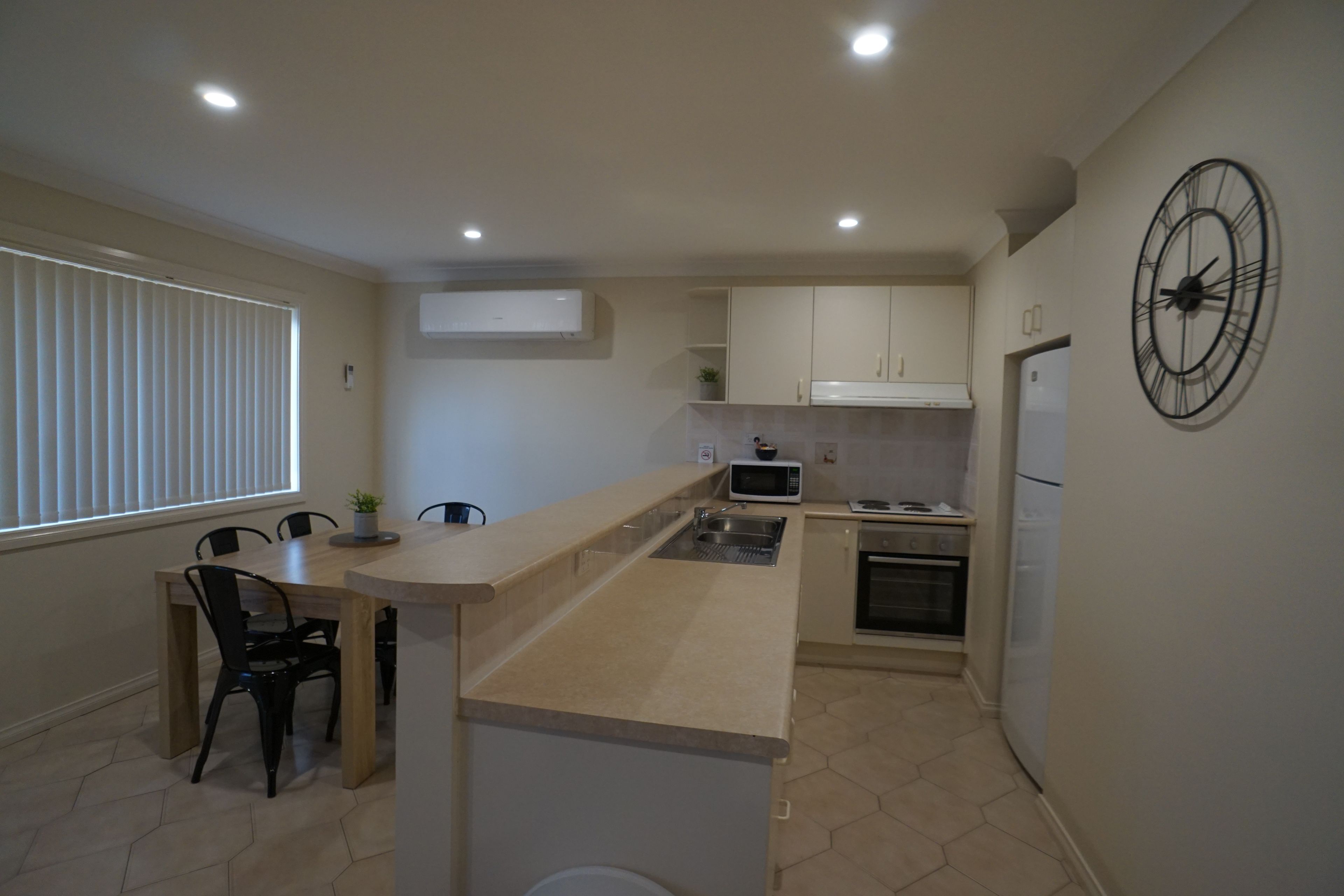 Una cocina compacta con una isla central, microondas, estufa y refrigerador.