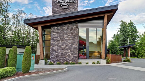 Un hotel Hampton Inn con fachada de piedra, ventanas amplias y un diseño moderno.