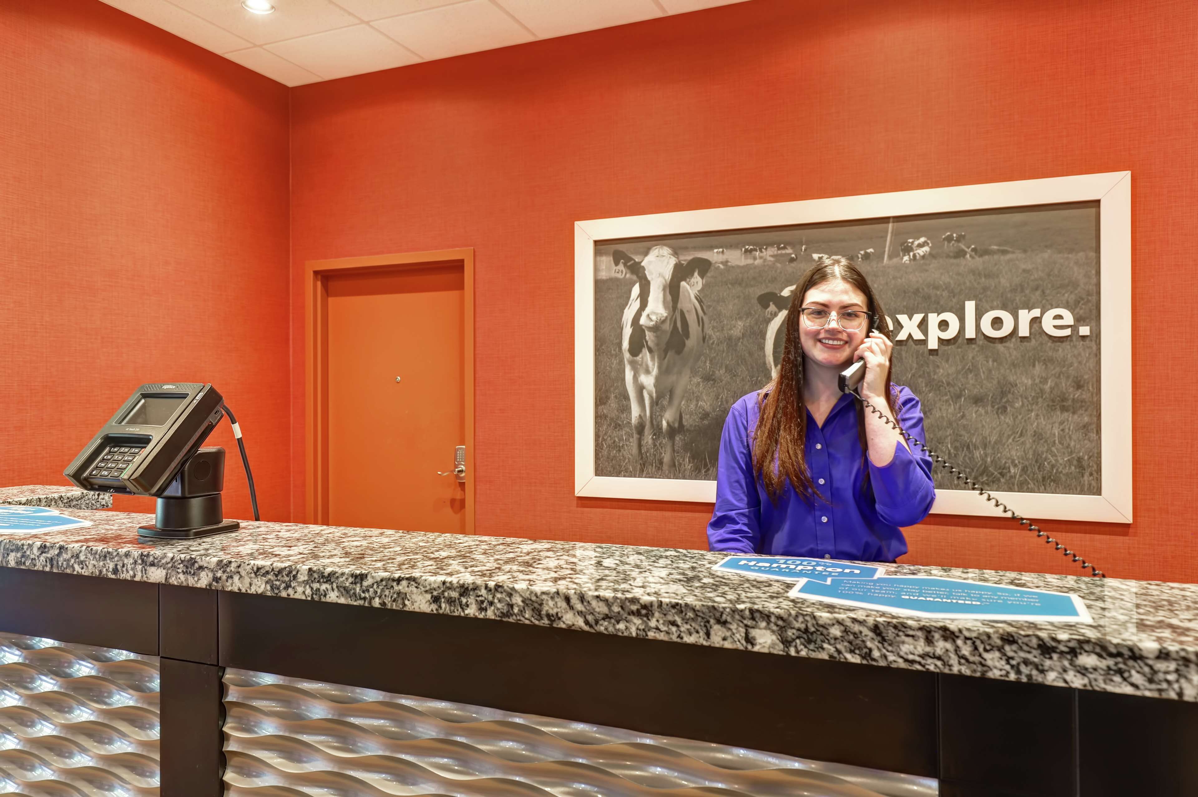 A reception desk with a phone, a framed picture of cows, and a sign that says "explore."