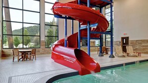 Un tobogán de agua en un área de piscina con una mesa y sillas cerca.