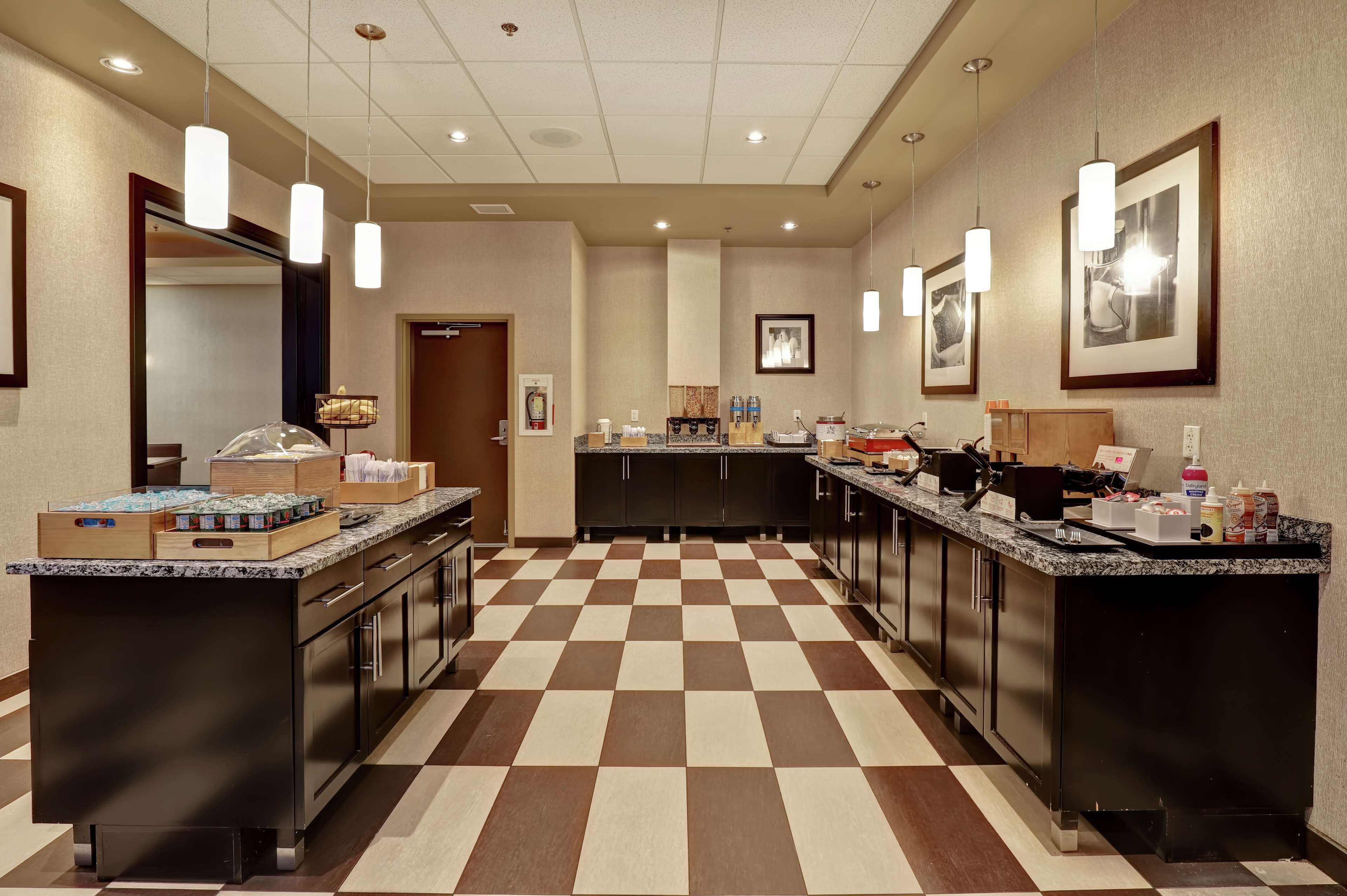 Una cocina de hotel con suelo de cuadros, iluminación colgante y una barra de autoservicio.