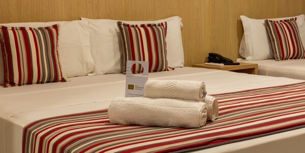 Habitación de hotel con una cama grande, dos almohadas, una mesita de noche con un teléfono y un cartel que indica los servicios de la habitación.