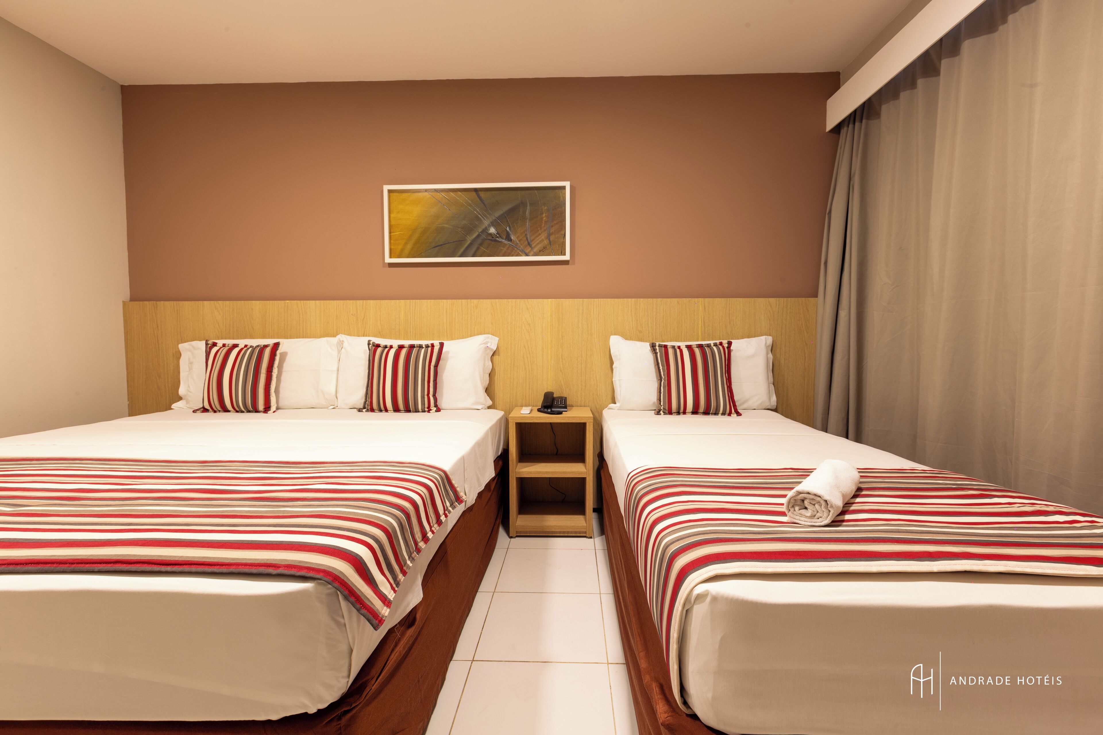 Ein Hotelzimmer mit zwei Betten, einem Holzkopfteil, einem Nachttisch und einem Bild an der Wand.