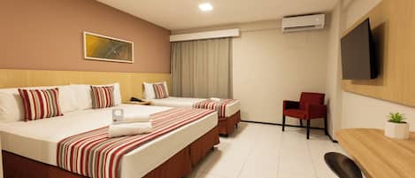 Habitación de hotel con dos camas, televisor, escritorio y una silla.