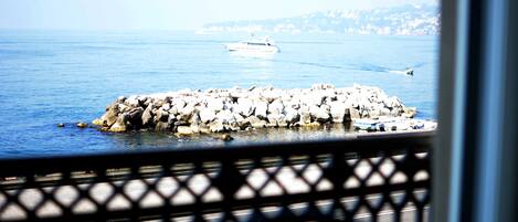 A rocky breakwater with boats, a clear sky, and a distant shoreline.