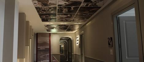 A modern hallway with a patterned ceiling, a red carpet, and a staircase.