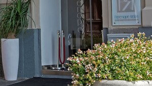 The entrance of Partenope Relais Boutique Hotel Naples with a blue awning, a glass door, and a signboard. - Partenope Relais (Naples)