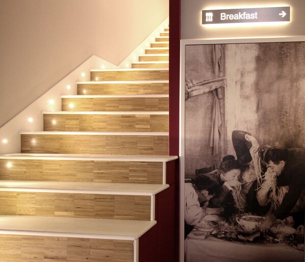 A staircase with wooden steps and white railings, leading to a breakfast area indicated by a sign. - Partenope Relais (Naples)
