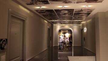 A hallway with a ceiling covered in black and white photographs, leading to a room with a view of a cityscape.