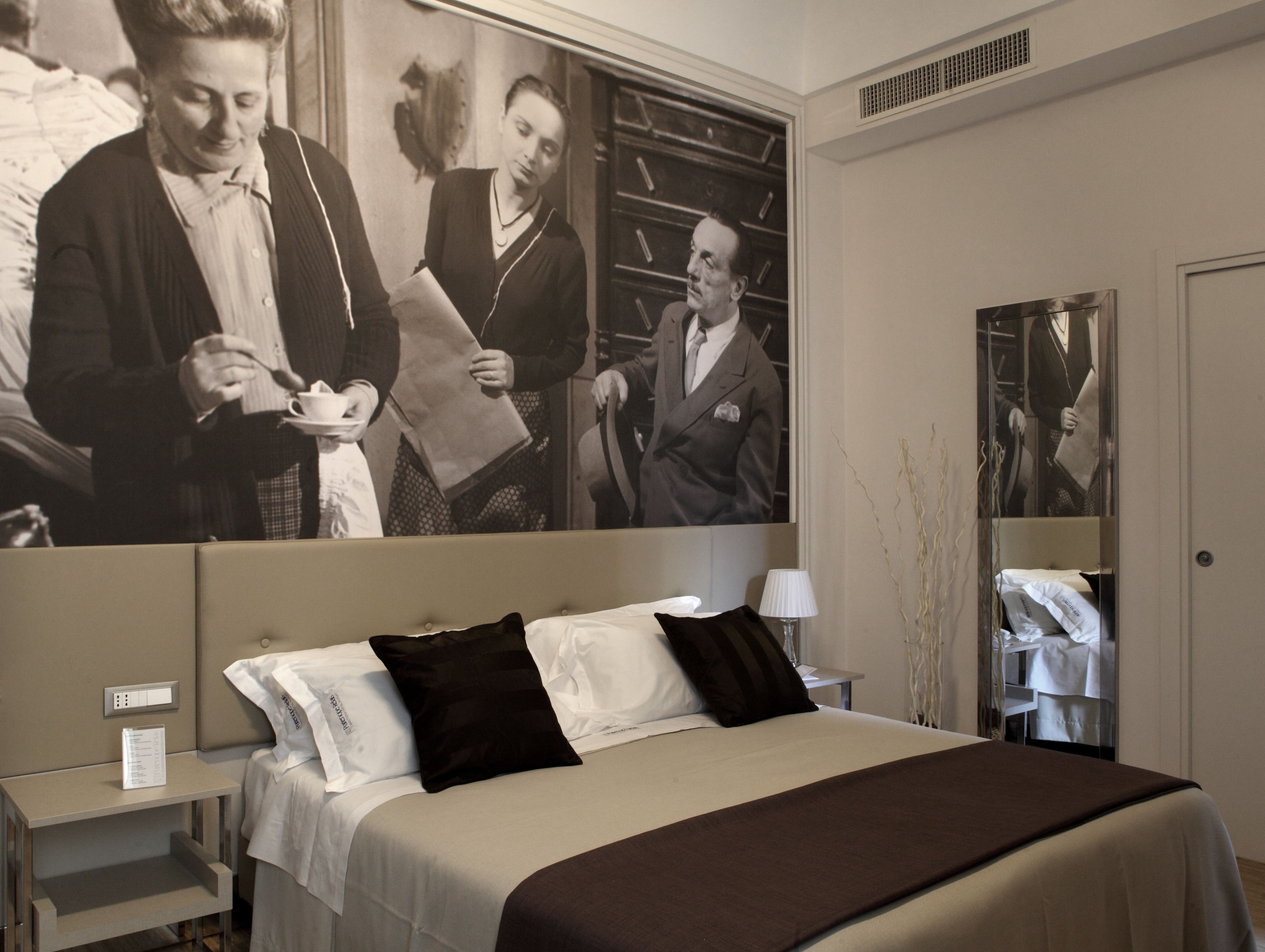 Ein modernes Hotelzimmer mit einem großen Bett, einem Nachttisch, einer Lampe und einem Spiegel.
