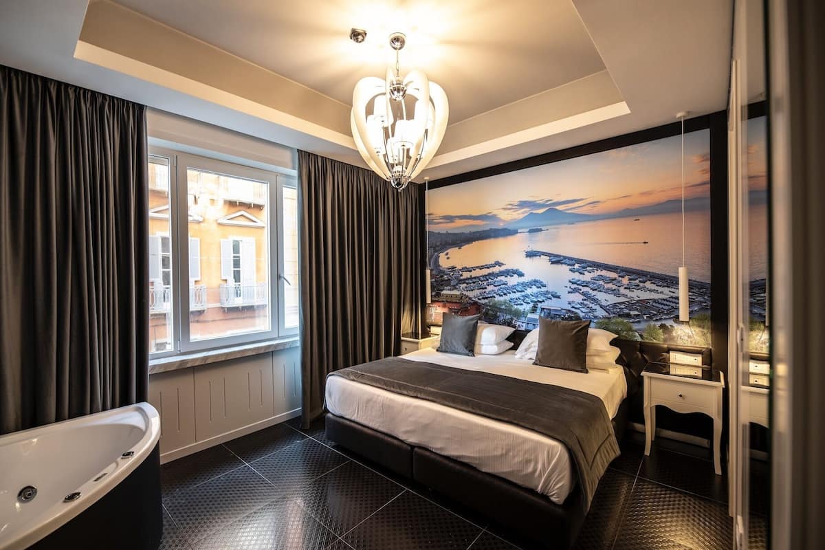 A modern hotel room with a large bed, a bathtub, and a cityscape view.