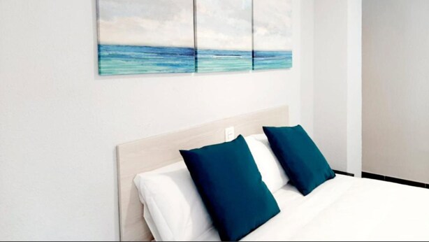 A hotel room with a bed, two pillows, and a wall with three paintings of the sea. - Hostal Lucía by gaiarooms (Salamanca)