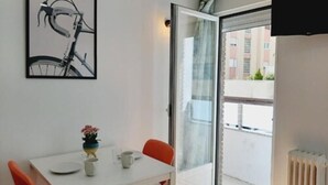 A modern room with a white table, two red chairs, a small potted plant, and a bicycle illustration on the wall. - Hostal Lucía by gaiarooms (Salamanca)