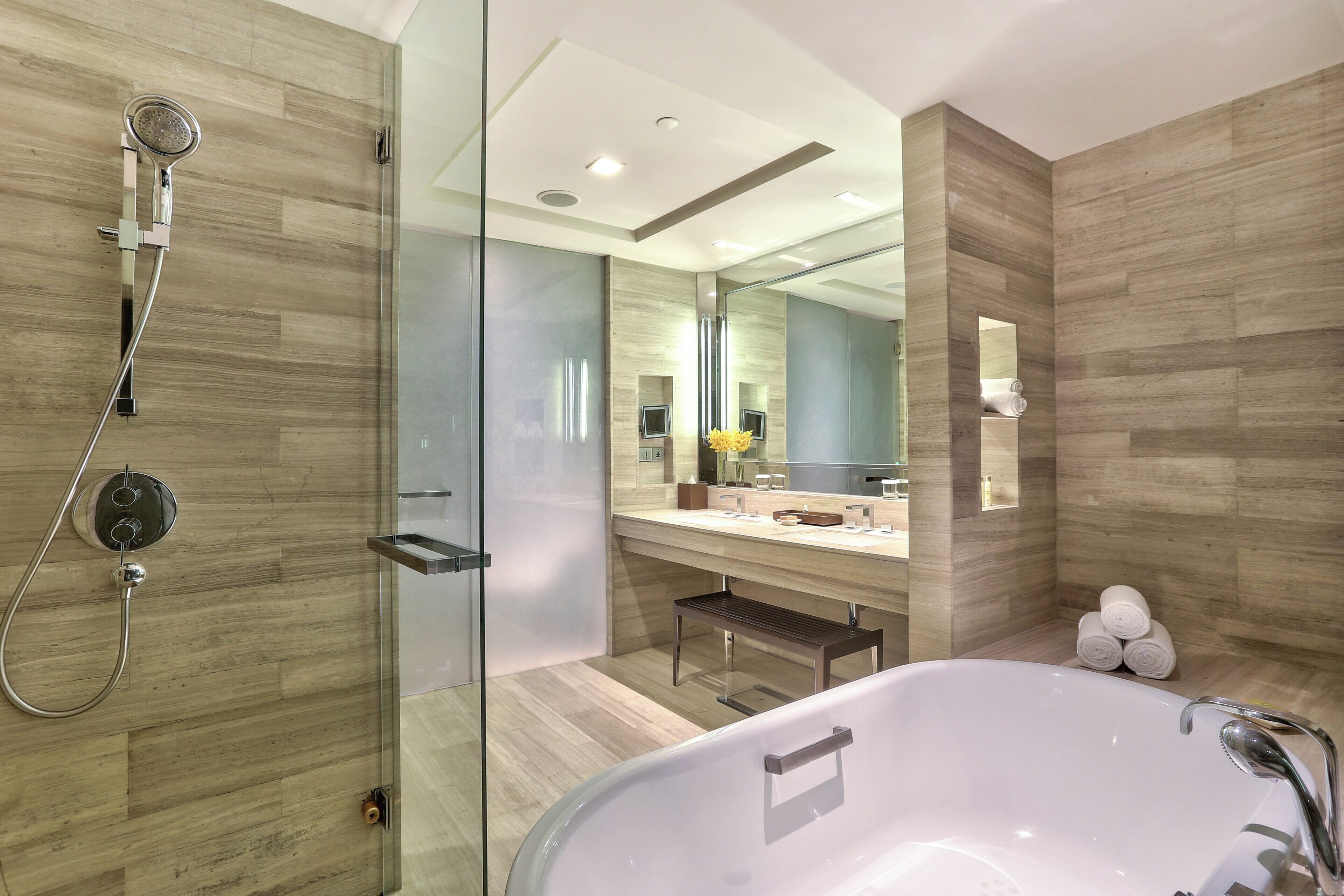 A modern bathroom with a glass-enclosed shower, a freestanding bathtub, and a vanity with a mirror.