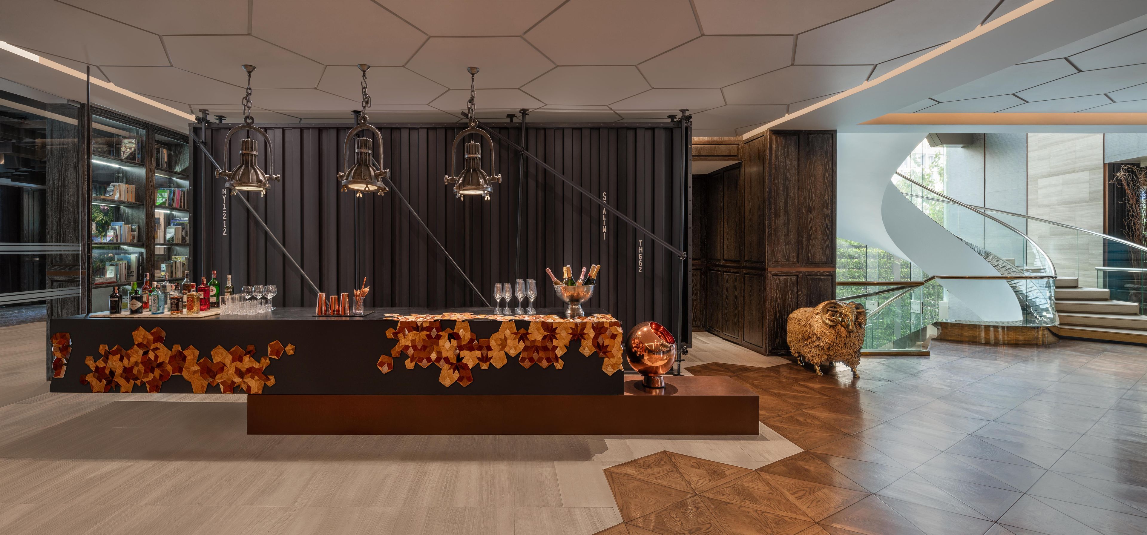 A modern bar area with a long counter, multiple hanging lights, and a decorative centerpiece.