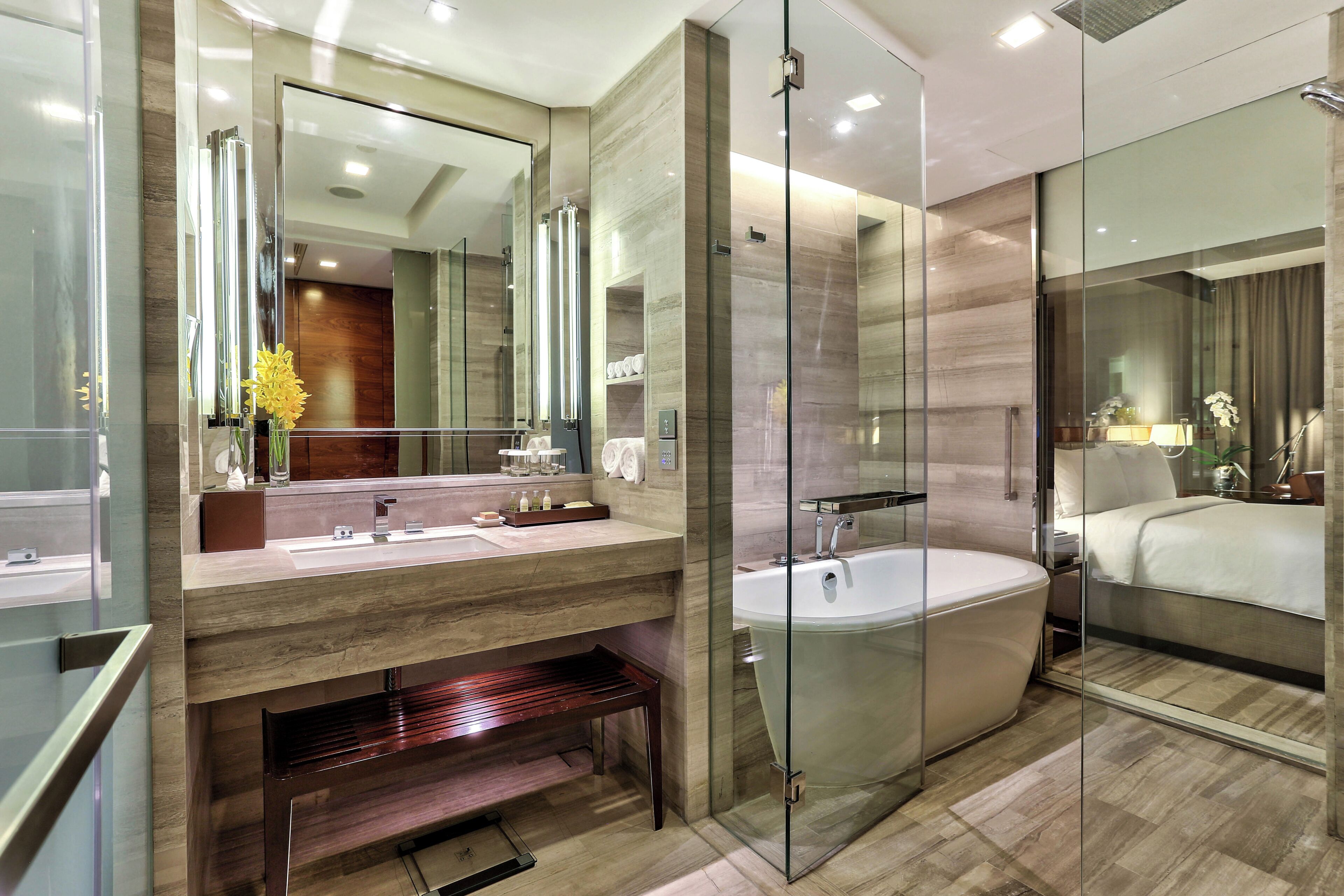 A modern bathroom with a glass-enclosed shower, a large mirror, and a bathtub.
