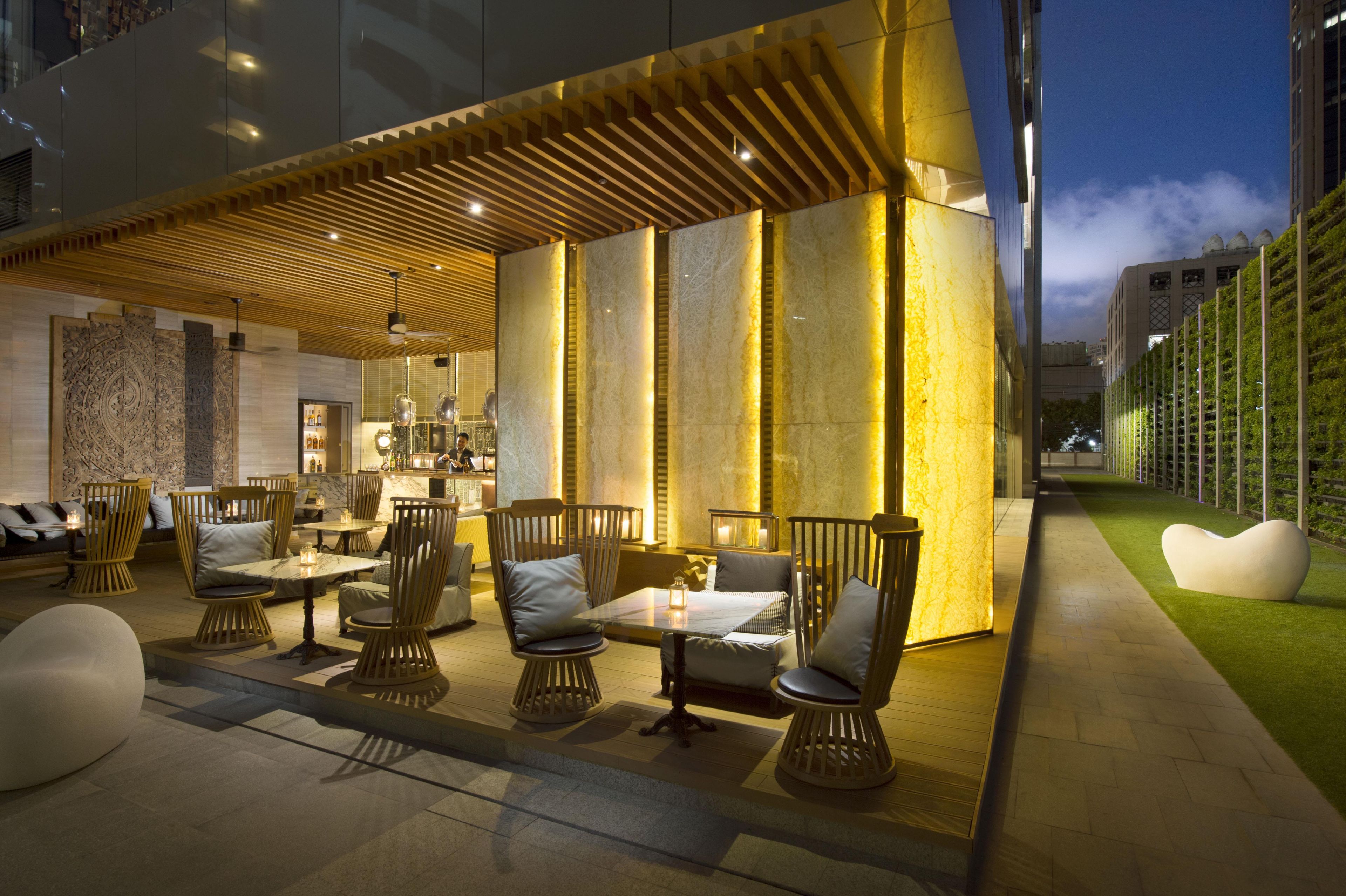 An outdoor seating area with tables and chairs, a bar, and a modern architectural design.