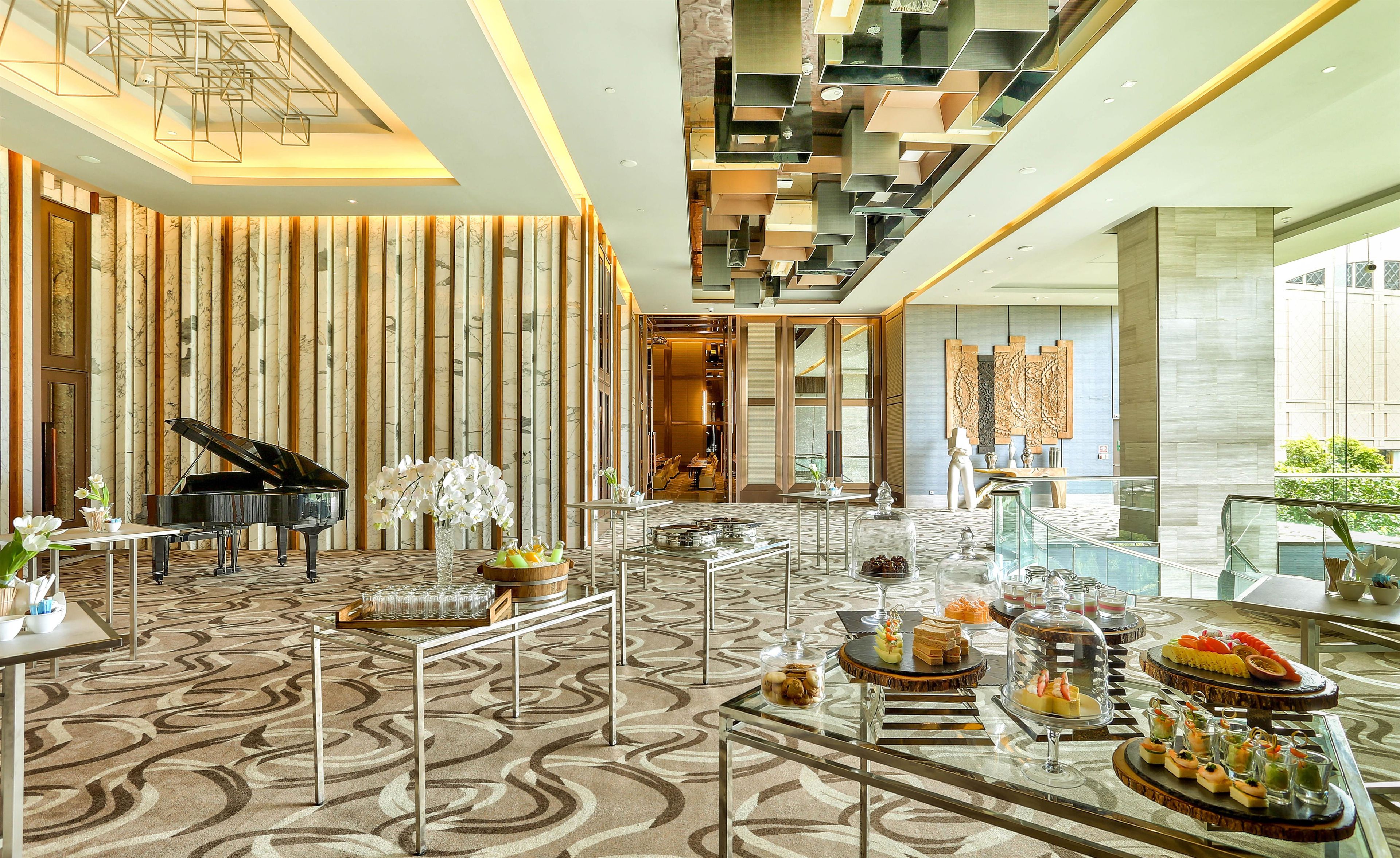 A spacious lobby with a grand piano, a marble-patterned floor, and a modern ceiling design.