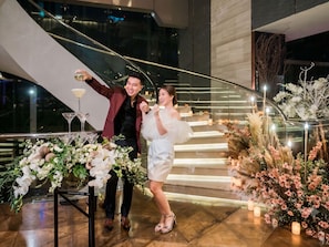 A staircase with a railing, a table with floral arrangements, and a glass railing. - Hilton Sukhumvit Bangkok (Bangkok)
