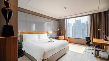 A hotel room with a large bed, a desk, a chair, and a view of the cityscape.