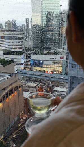 Vista urbana com edifícios modernos, incluindo uma loja Zara, e uma pessoa segurando um copo.