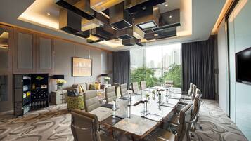 A modern conference room with a large table, chairs, and a city view.