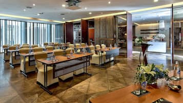 A conference room with tables and chairs, a kitchen area, and a large window with a view.