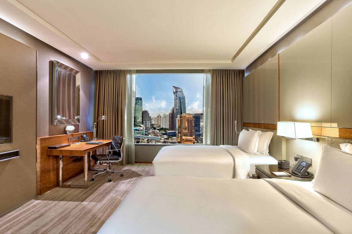 Une chambre d’hôtel avec vue sur la ville, un bureau, un lit et un téléphone.