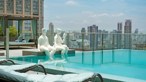 Une piscine sur le toit, dotée de chaises longues et offrant une vue sur la ville.