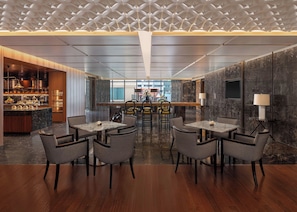 Un restaurant moderne doté d’un bar central, de nombreuses tables et de chaises.
