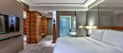 Una habitación de hotel con una cama grande, televisión, armario de madera, baño y espejo.