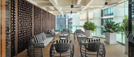 Un espace de détente moderne, avec des meubles en osier, un meuble à vin et une vue sur le paysage urbain.