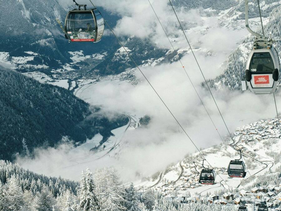 Sistema de teleférico en una zona montañosa nevada, con vistas claras del valle.