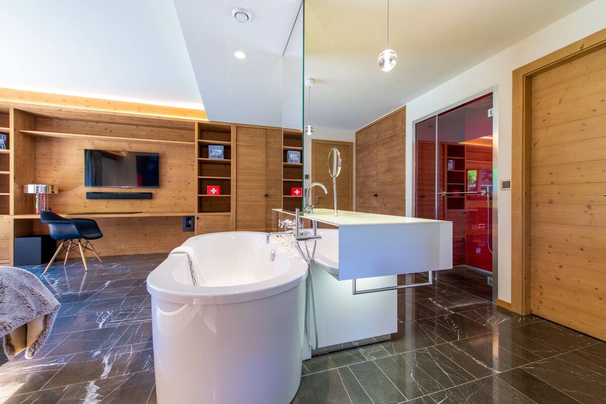 Un baño moderno con una bañera independiente, un tocador con espejo y estanterías de madera.