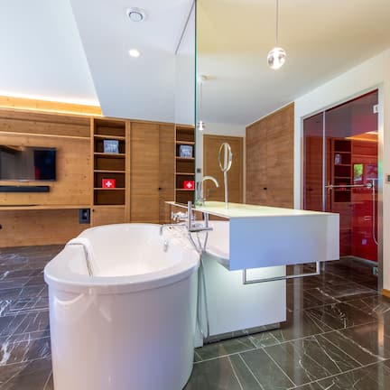 A modern bathroom with a freestanding bathtub, a vanity with a mirror, and wooden shelving.