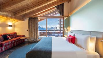 A bedroom with a bed, a sofa, a small table, and a view of mountains.