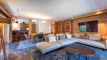 A modern living room with a sectional sofa, a coffee table, and a dining area with chairs and a table.